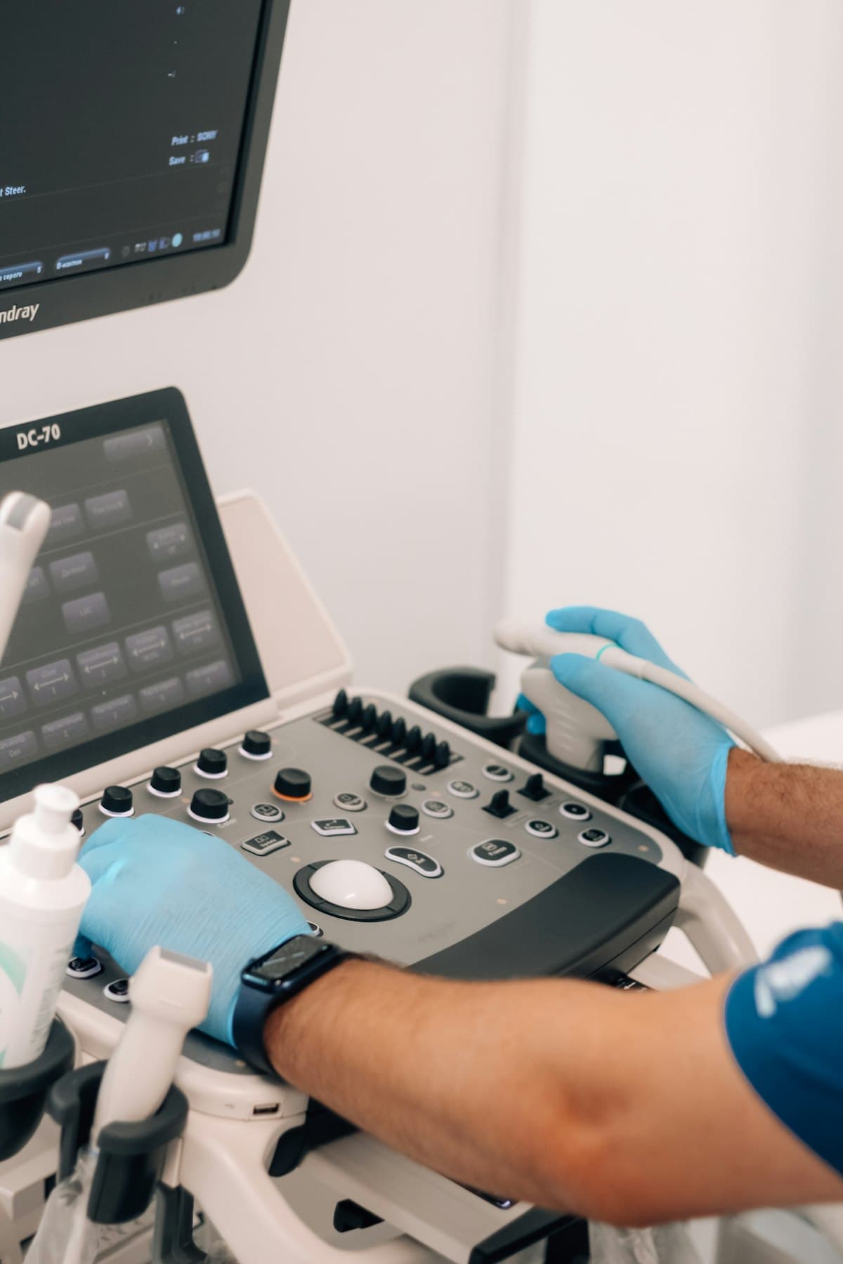 Gloved hands operating the control panel of an ultrasound and Doppler machine