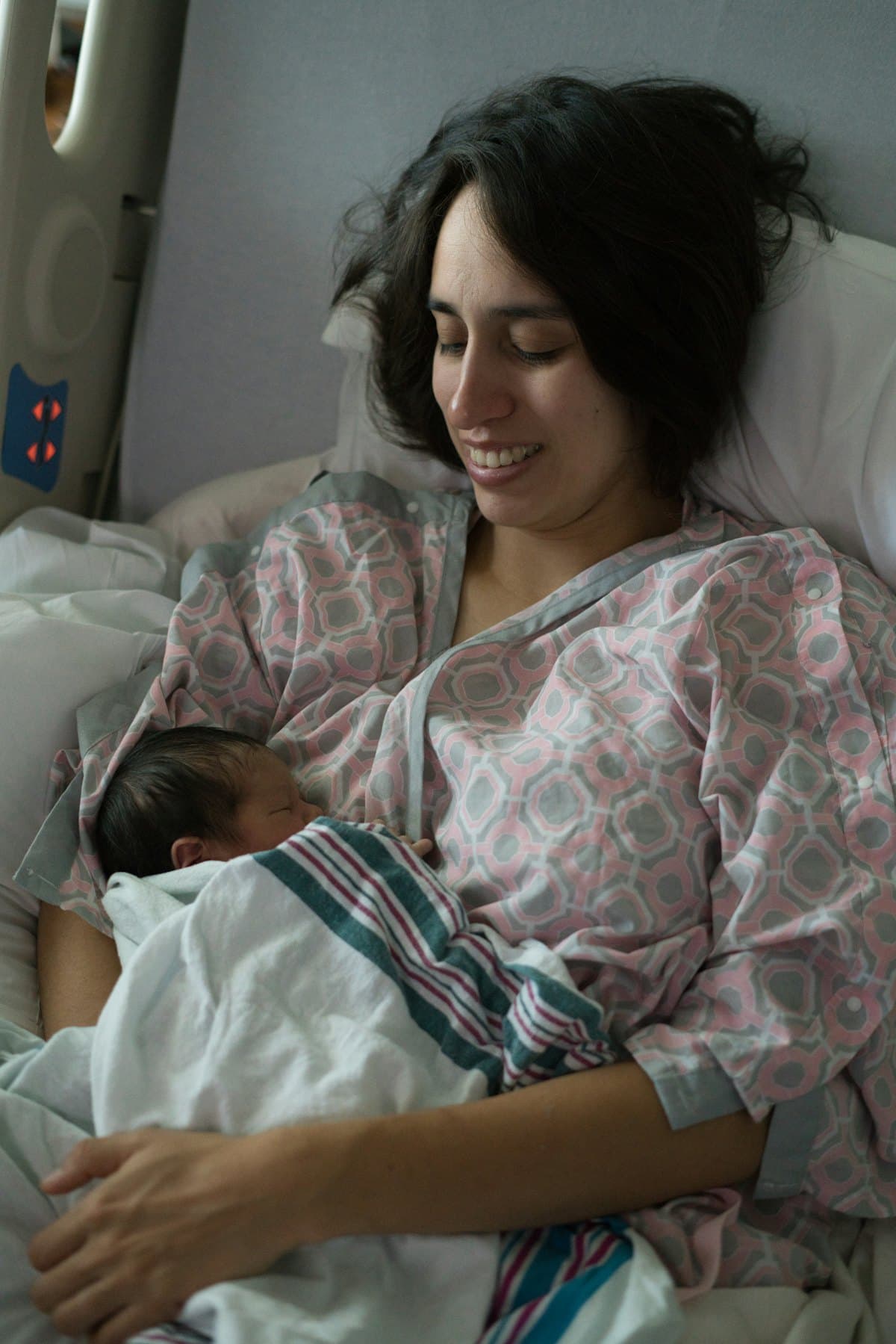 A mother holding her newborn in a hospital bed